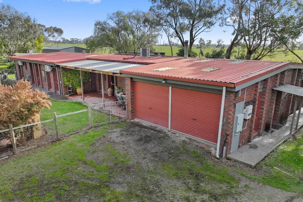 57 Williamsons Road, Yarragon — the red-brick house and its twin garaging from above, paddocks beyond