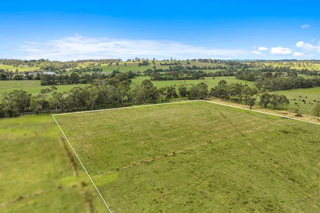 10/40 Edgar Road, Longwarry — the block outlined from the air, grazing country and a treed windbreak beyond